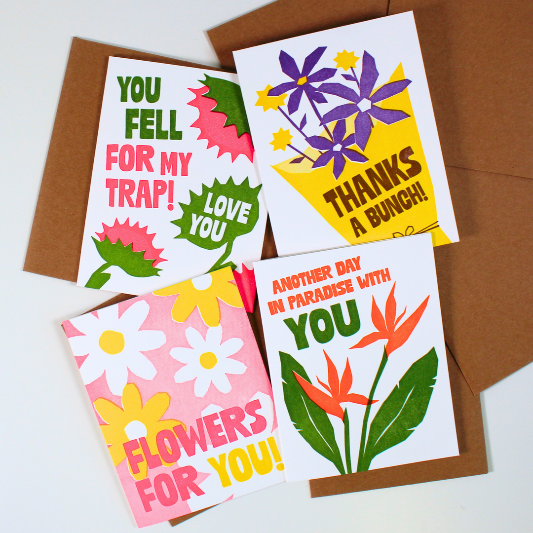 Three colorful floral greeting cards with brown envelopes, arranged on a white background. The cards feature playful text and bright flower illustrations in pink, yellow, purple, green, and white.
